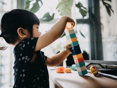 Toddler girl stacks coloured blocks