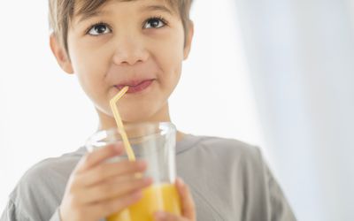 young boy drinking juice with straw