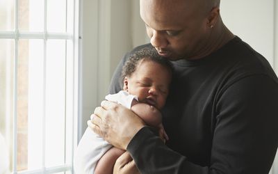 Father holding baby boy beside a sunny window