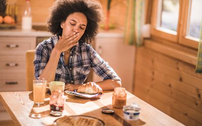 年轻的非裔美国妇女在餐厅吃早餐时感到恶心