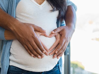 A couple with hands in a heart shape on the woman's pregnant belly