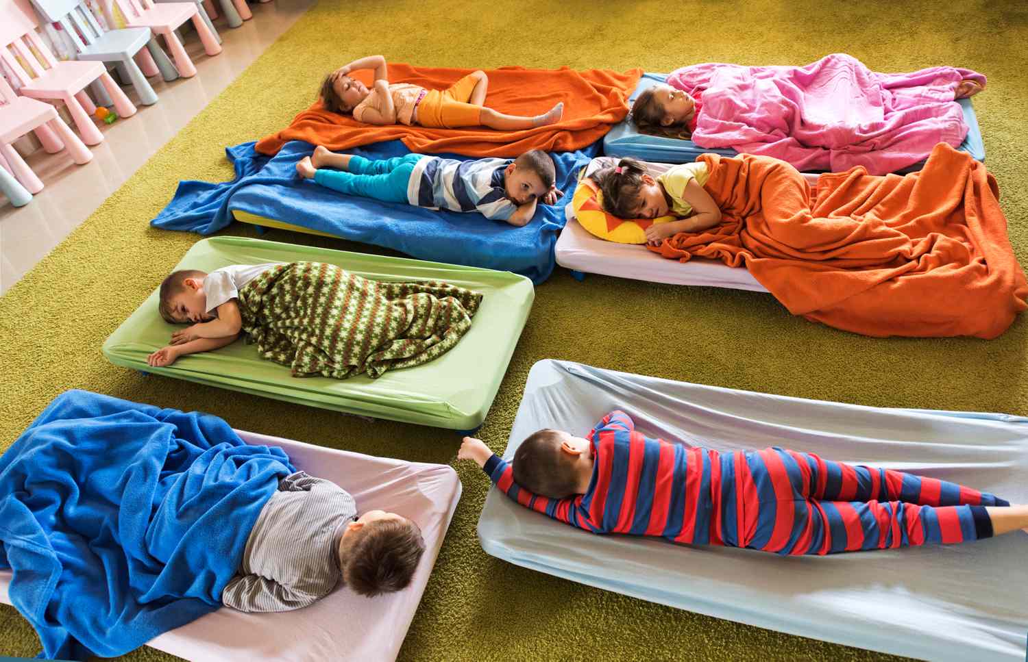 Preschoolers nap on cots