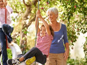 Grandparent helping grandkids on tire swings