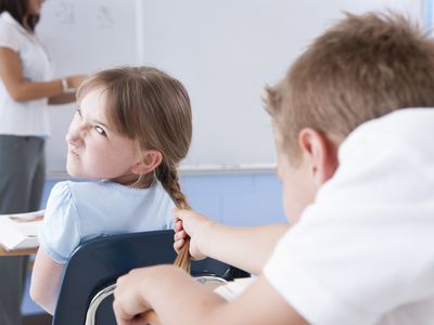 boy pulling girl's braid in class