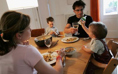 Mother and father sitting at the table with a baby and toddler