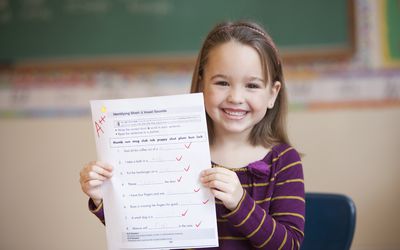 一个微笑的小女孩拿着一张评分为A++的试卷