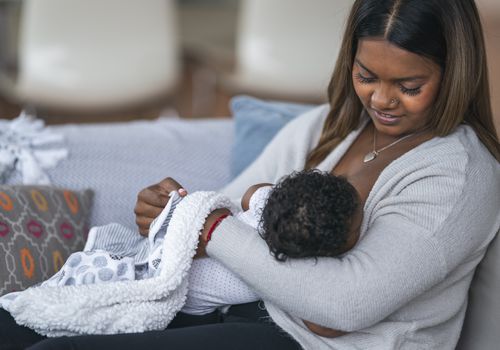 Woman nursing baby at home