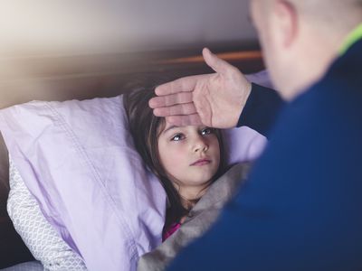 father checking daughter's forehead for fever