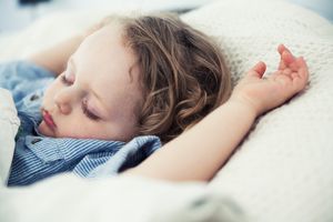 睡觉的蹒跚学步的男孩，手臂放在枕头上＂width=
