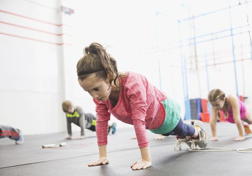 儿童力量训练-女孩在健身房保持平板支撑姿势