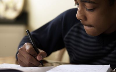 Close-up of boy (12-13) doing homework at desk