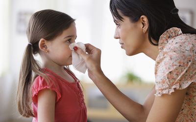 parent helping a child blow their nose