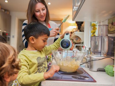 Woman helping kids with a mixer in the kitchen