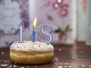 iced donut with candles spelling out the number 18