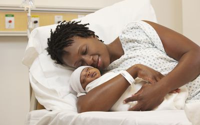 在病床上抱着新生儿的黑人妇女
