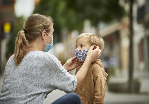 妈妈给她年幼的儿子戴上口罩