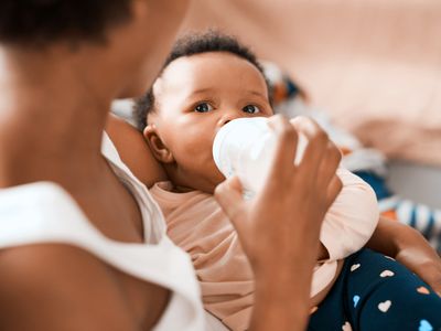 Mother feeding child with baby bottle