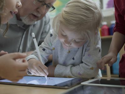 Close up preschool girl with stylus drawing on digital tablet